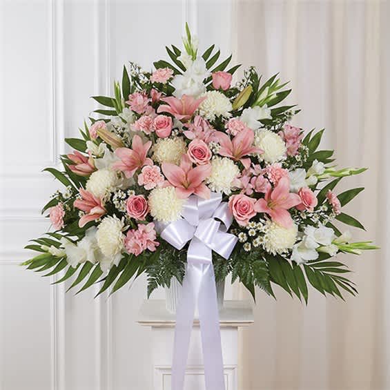 Pink and white floral spray with a white ribbon bow on a stand