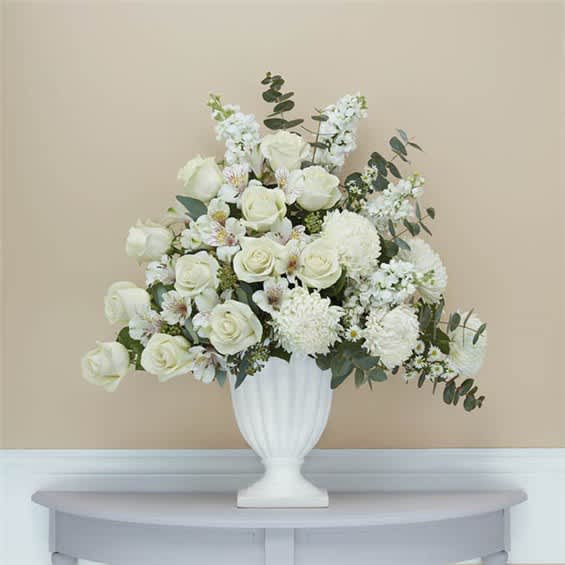 White rose and chrysanthemum arrangement in a white urn vase