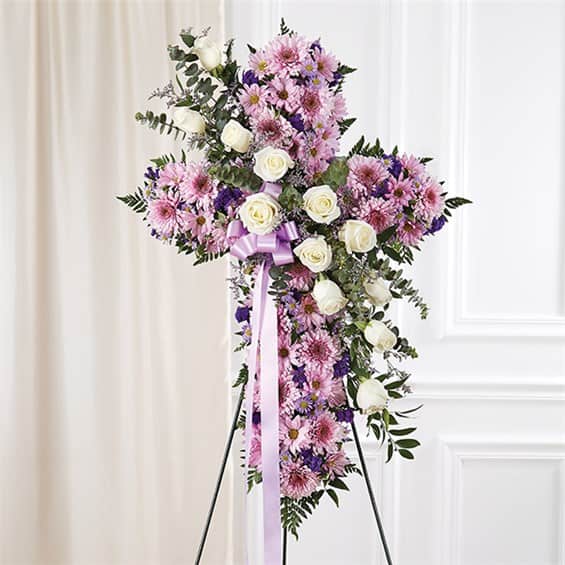 Standing floral cross with pink and white flowers on an easel
