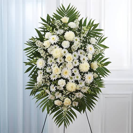 White funeral standing spray with mixed blooms and palm fronds