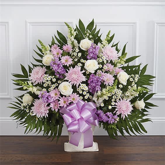 Lavender and white floral arrangement in a white container with a purple bow