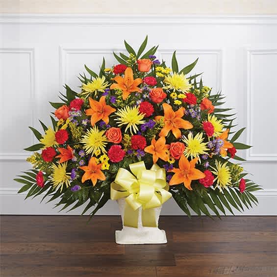 Large mixed flower arrangement in a white basket with a yellow bow