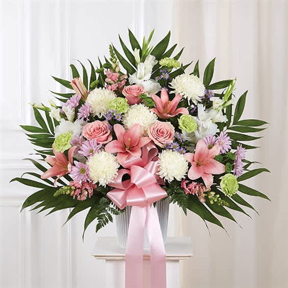 Pink and white floral arrangement in a vase with a pink ribbon