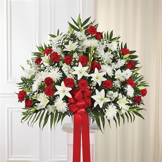Large red and white floral standing arrangement with a red ribbon bow