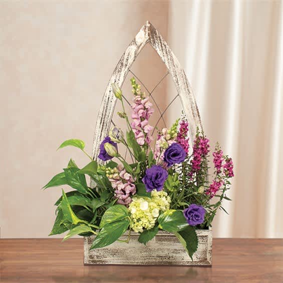 Purple and pink flowers arranged in a rustic wooden basket with a handle