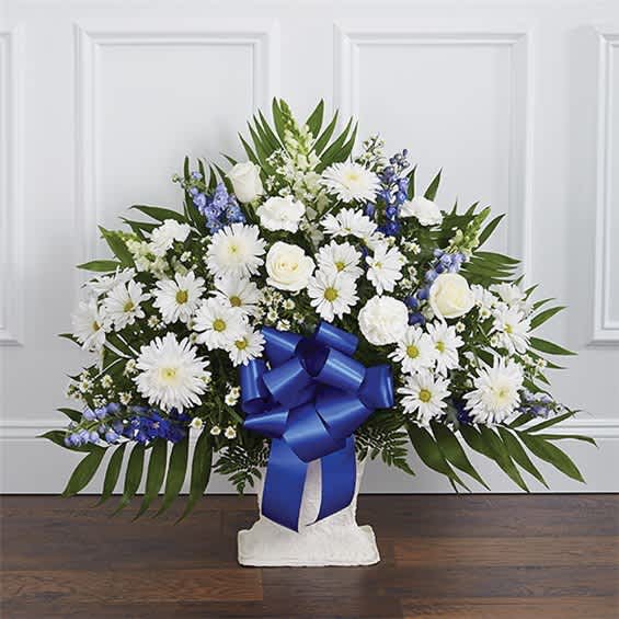 White daisies and roses in a white vase with a blue ribbon