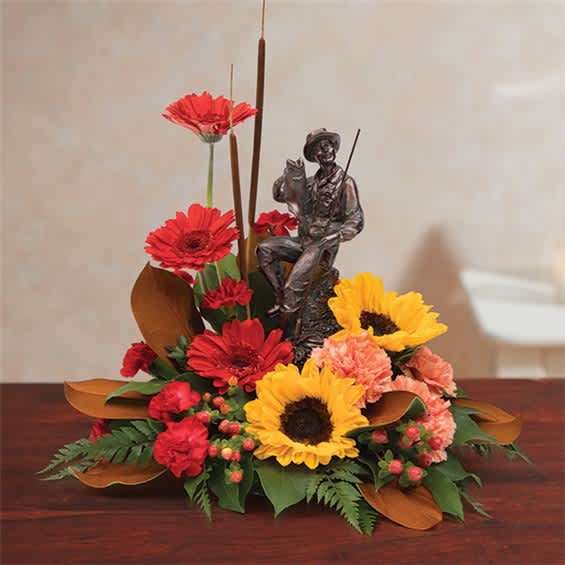 Arrangement with red gerberas, yellow sunflowers, and a small fisherman figurine