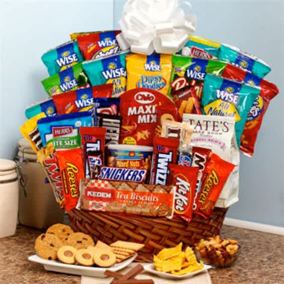 Basket filled with assorted snack bags and candy bars, with cookies and chips in front