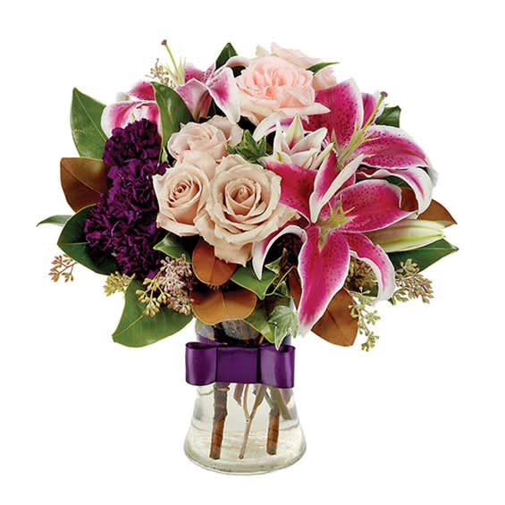 Bouquet of pink lilies and pale roses in a glass vase with a purple ribbon
