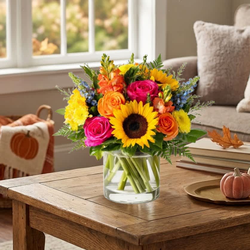 Bright mixed bouquet in a clear glass vase with sunflowers and roses