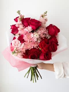Bouquet of red roses and pale pink flowers wrapped in white and pink paper
