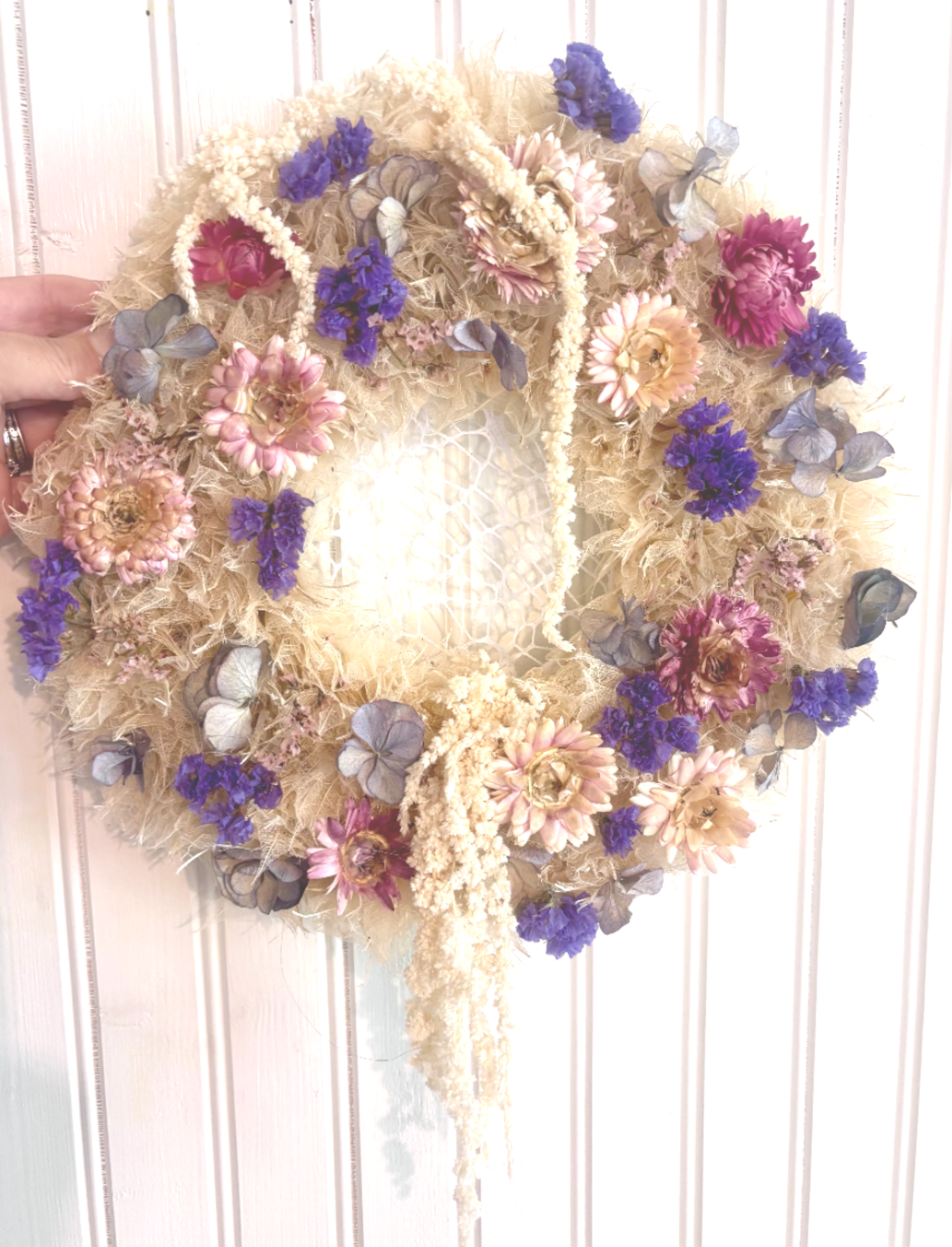 Dried floral wreath with purple and pink flowers on a straw base