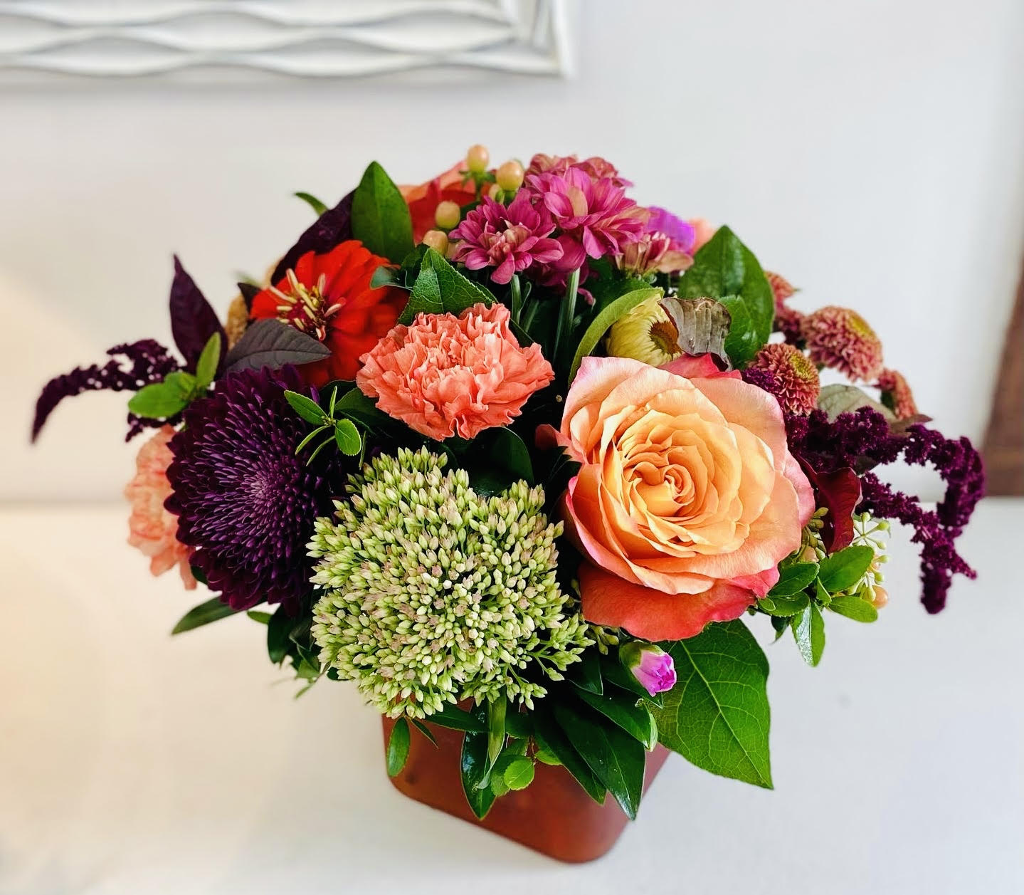 Mixed bouquet with peach rose, coral carnation, and purple blooms in a vase