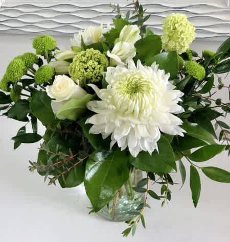 White and green floral arrangement in a glass vase