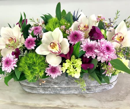 White orchids and pink flowers in a gray container