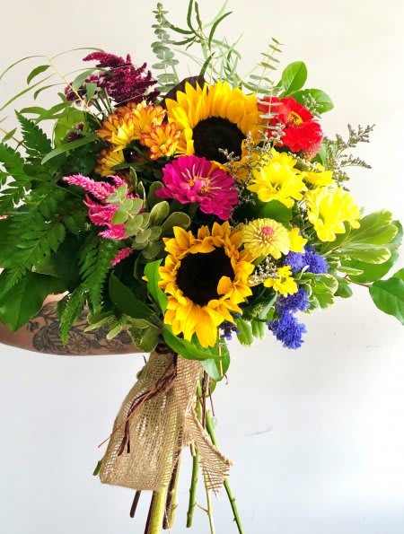 Hand-tied bouquet with bright yellow sunflowers, mixed colorful blooms, and burlap wrap