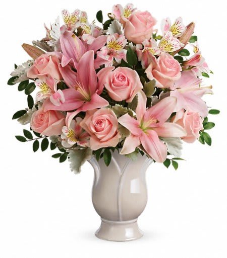 Pink roses and lilies arranged in a white vase