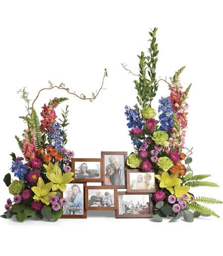 Colorful twin floral sprays with lilies and mixed blooms surrounding a wooden multi-photo frame