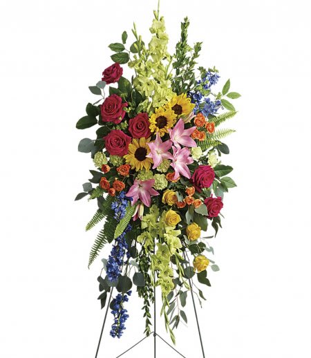 Tall standing floral spray with roses, lilies, sunflowers, and blue accents