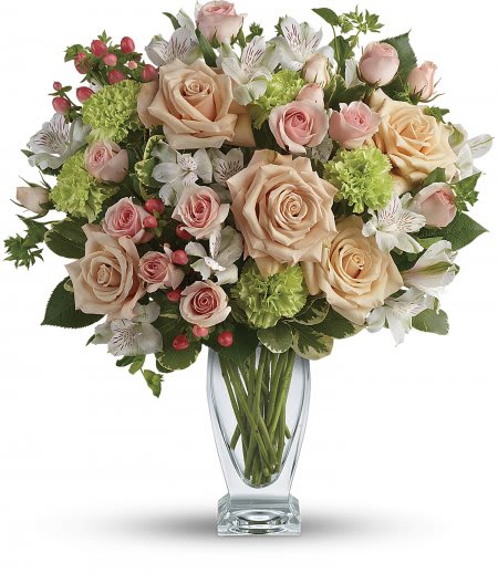 Tall glass vase of peach roses, pink spray roses, green carnations, and white alstroemeria