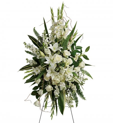 Tall standing spray of white lilies and roses with lush greenery on a metal easel.