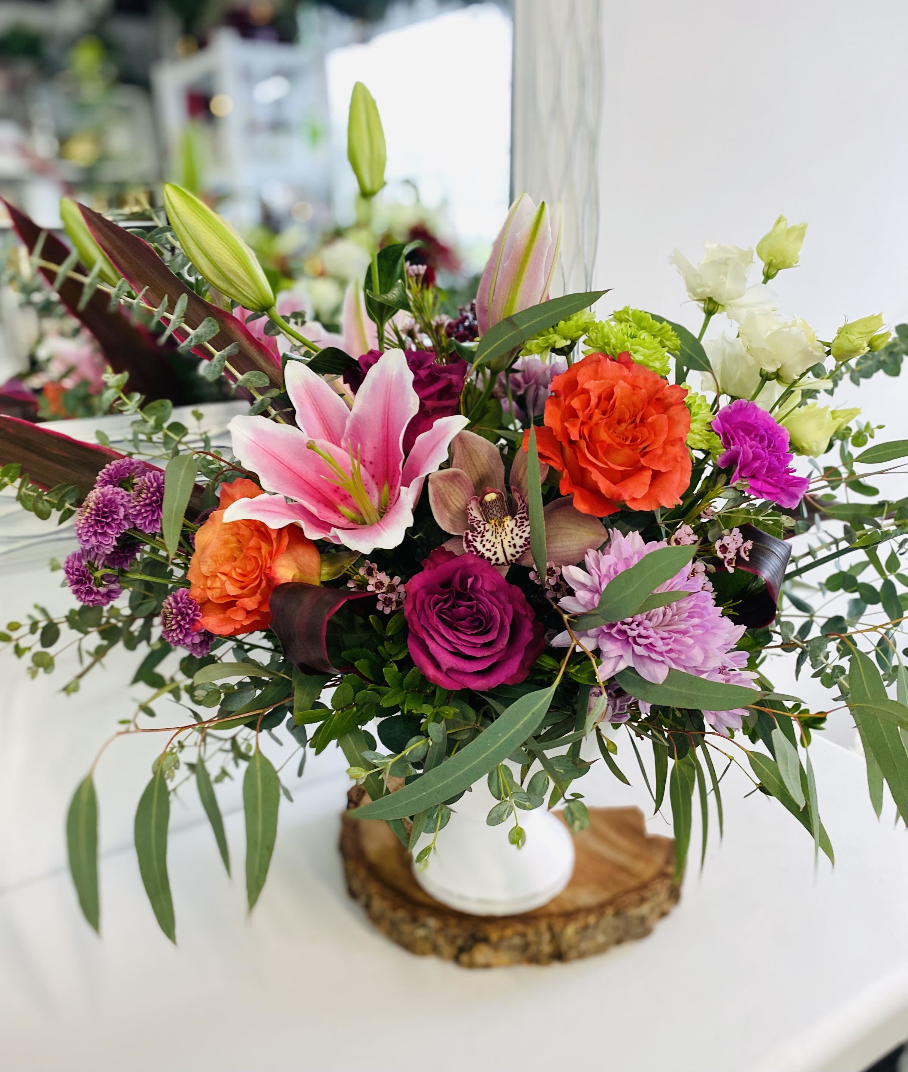 Colorful mixed bouquet in a white vase with lilies, roses, and chrysanthemums