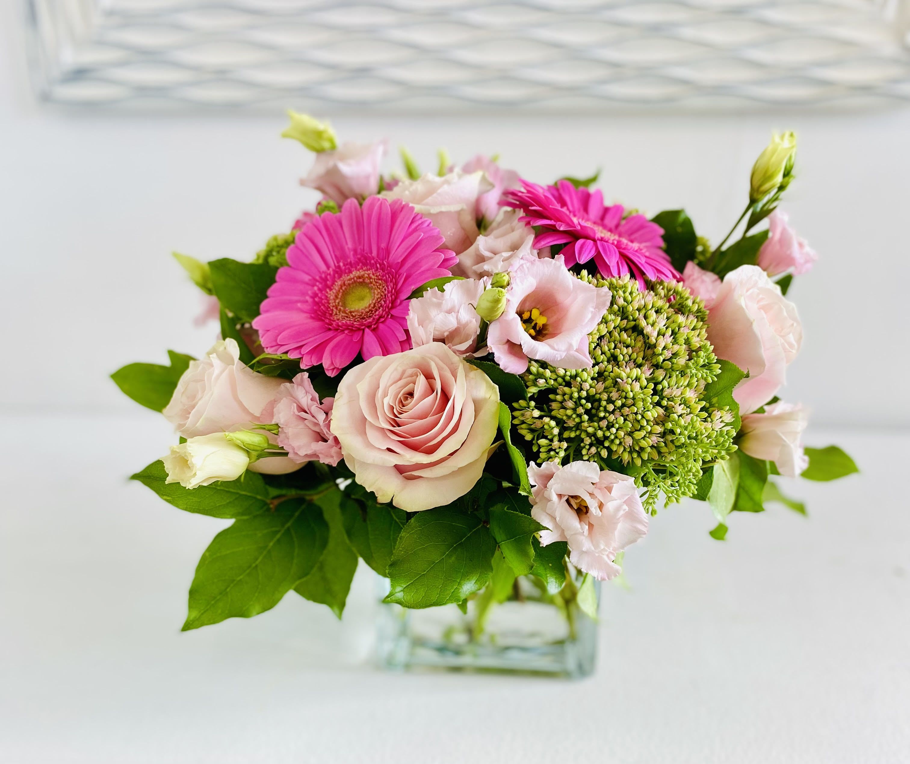 Pink roses and gerbera daisies in a clear glass vase