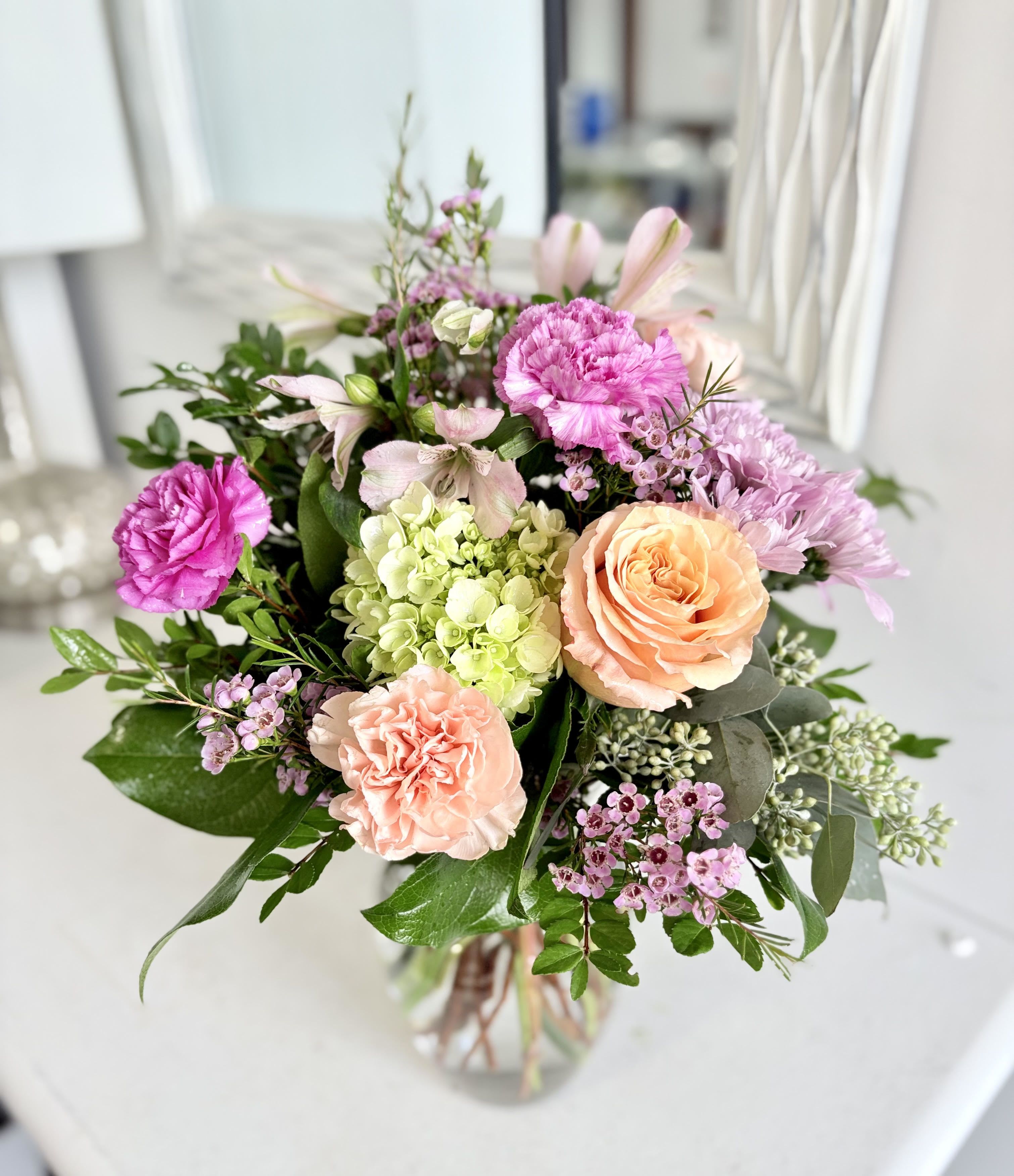 Bouquet of pink and peach flowers in a clear glass vase