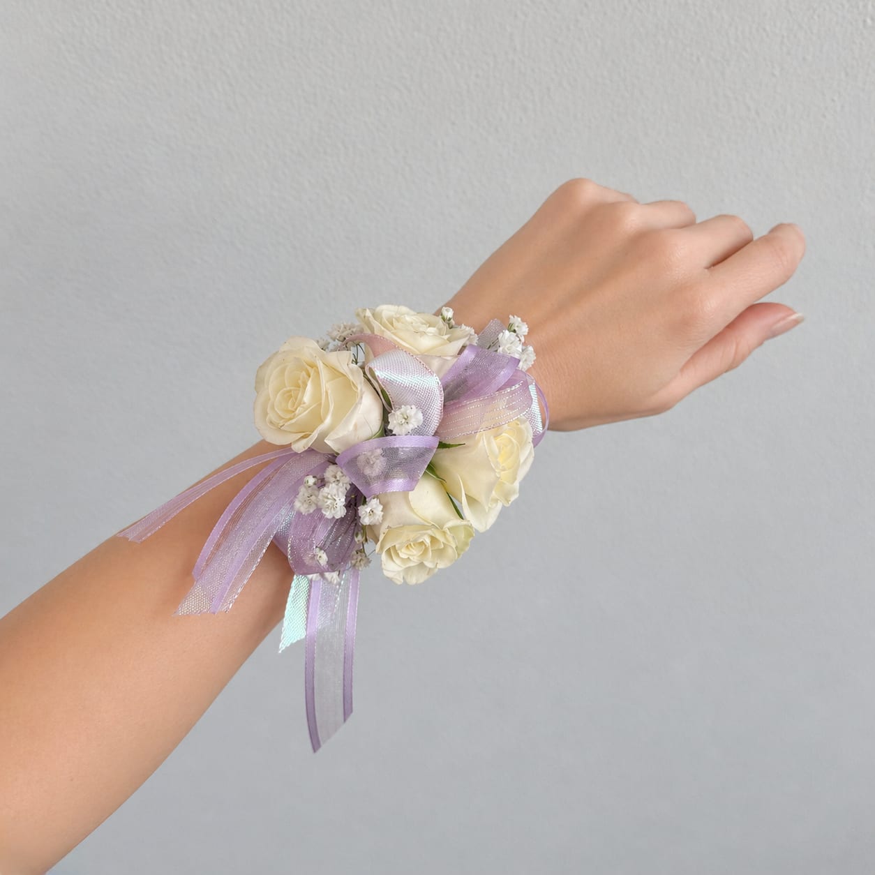 Cream rose wrist corsage with lavender ribbon on a person's wrist