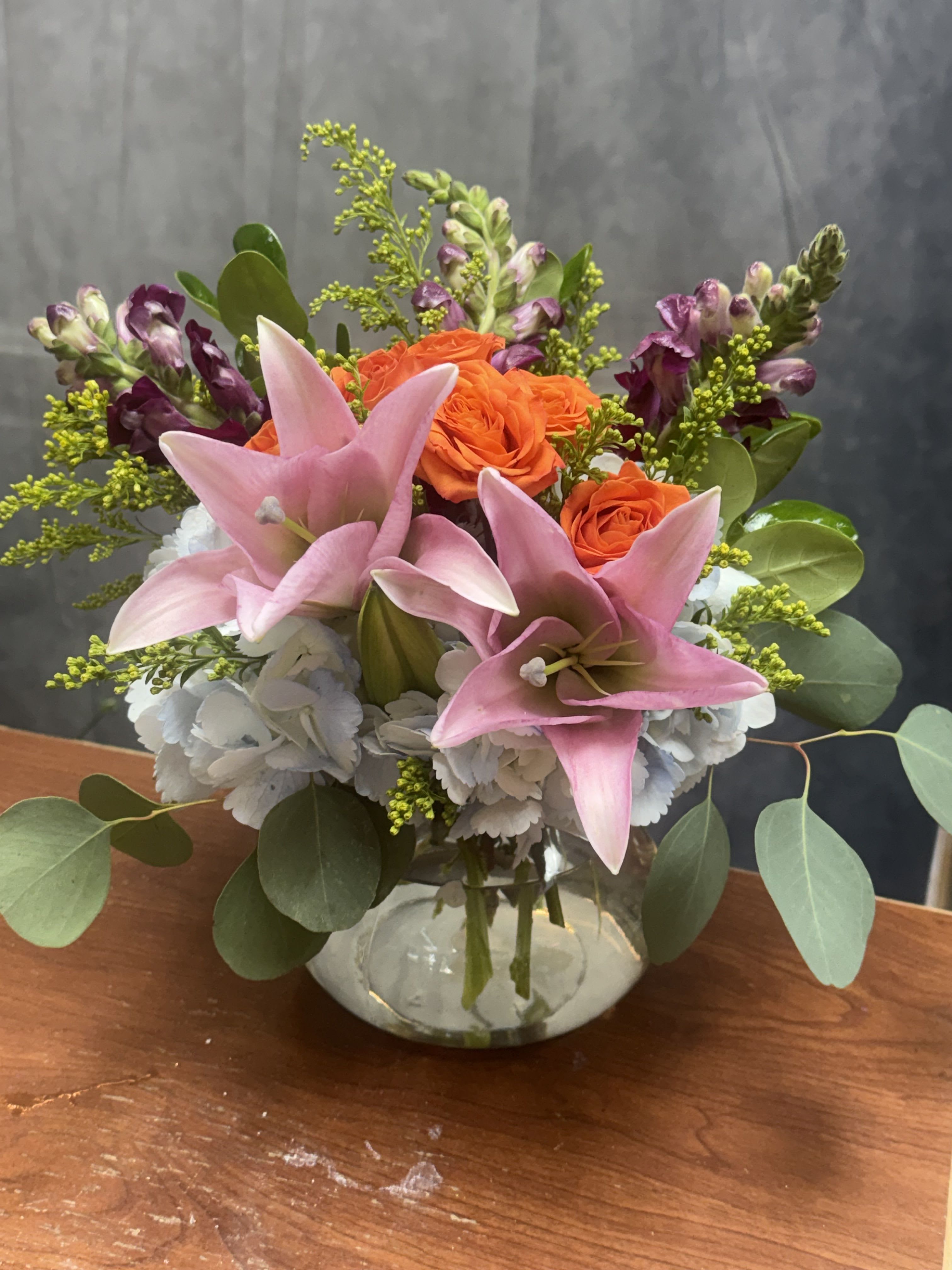Flamingo Sunset - Flamingo Sunset is a vibrant floral arrangement bursting with warmth and elegance. Featuring lush hydrangeas, graceful lilies, striking snapdragons, and delicate spray roses in shades of pink, orange, and yellow. Perfect for brightening any space, celebrating a special moment, or simply bringing joy with its radiant charm.