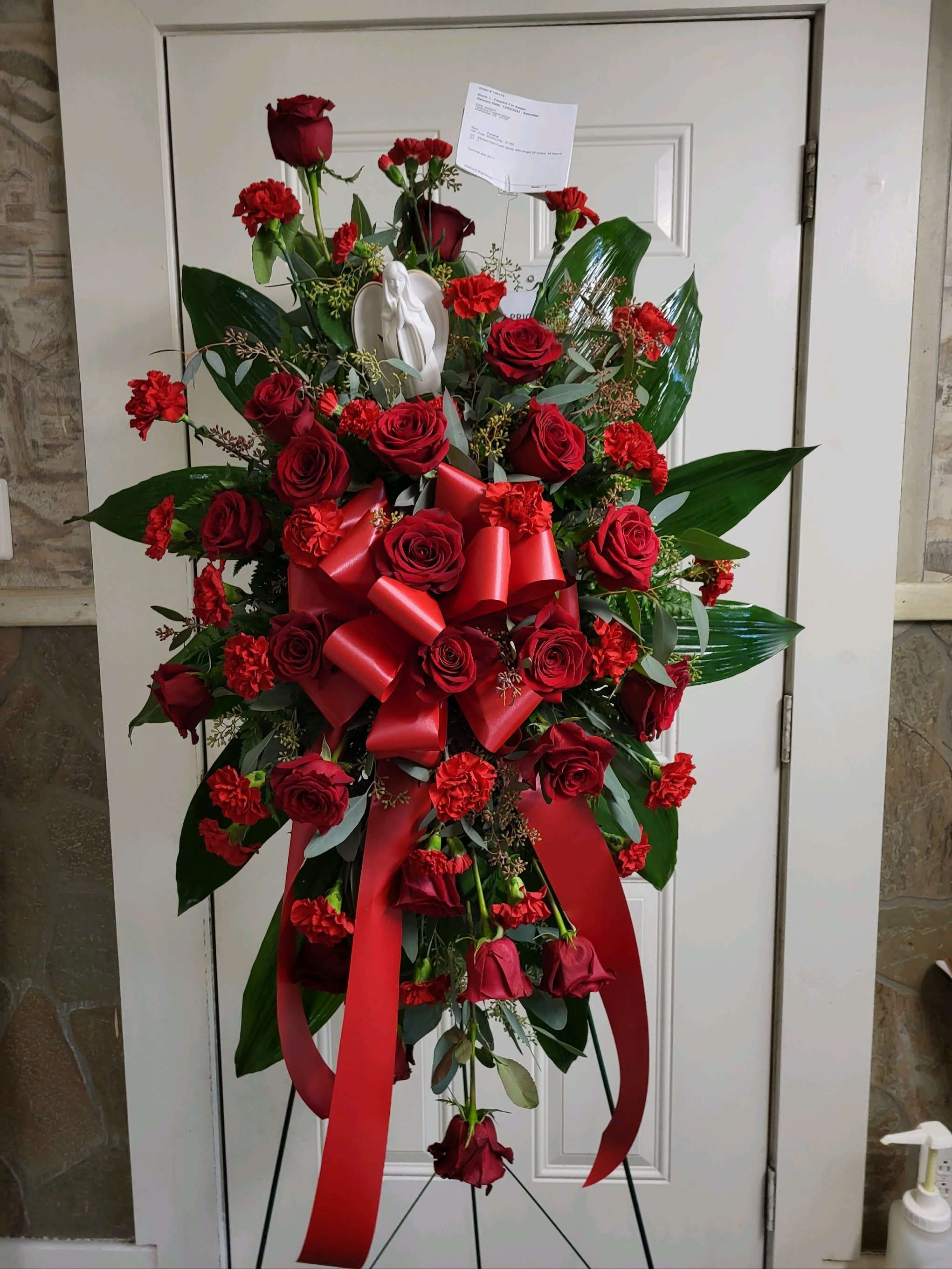 Standing spray of red roses and carnations with a red ribbon bow