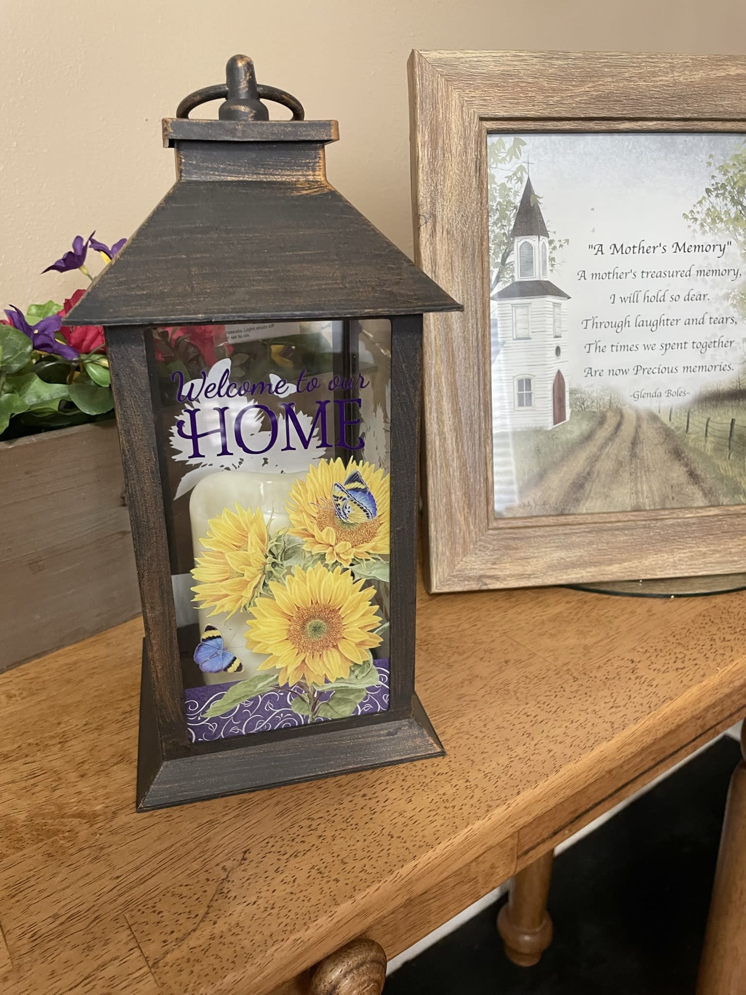 Decorative lantern with sunflower artwork and a memorial frame beside it