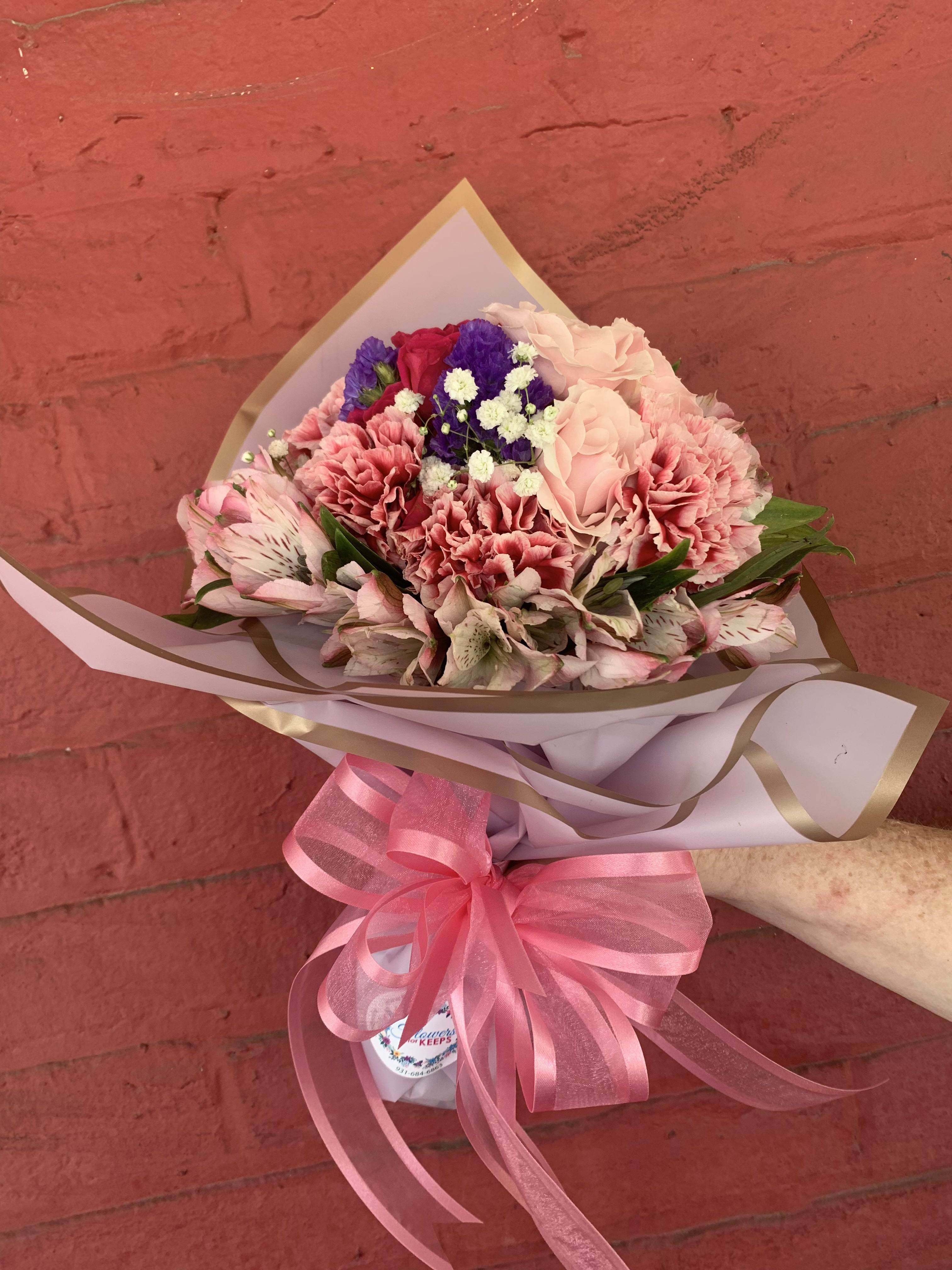 Pink and purple mixed bouquet wrapped in paper with a pink ribbon