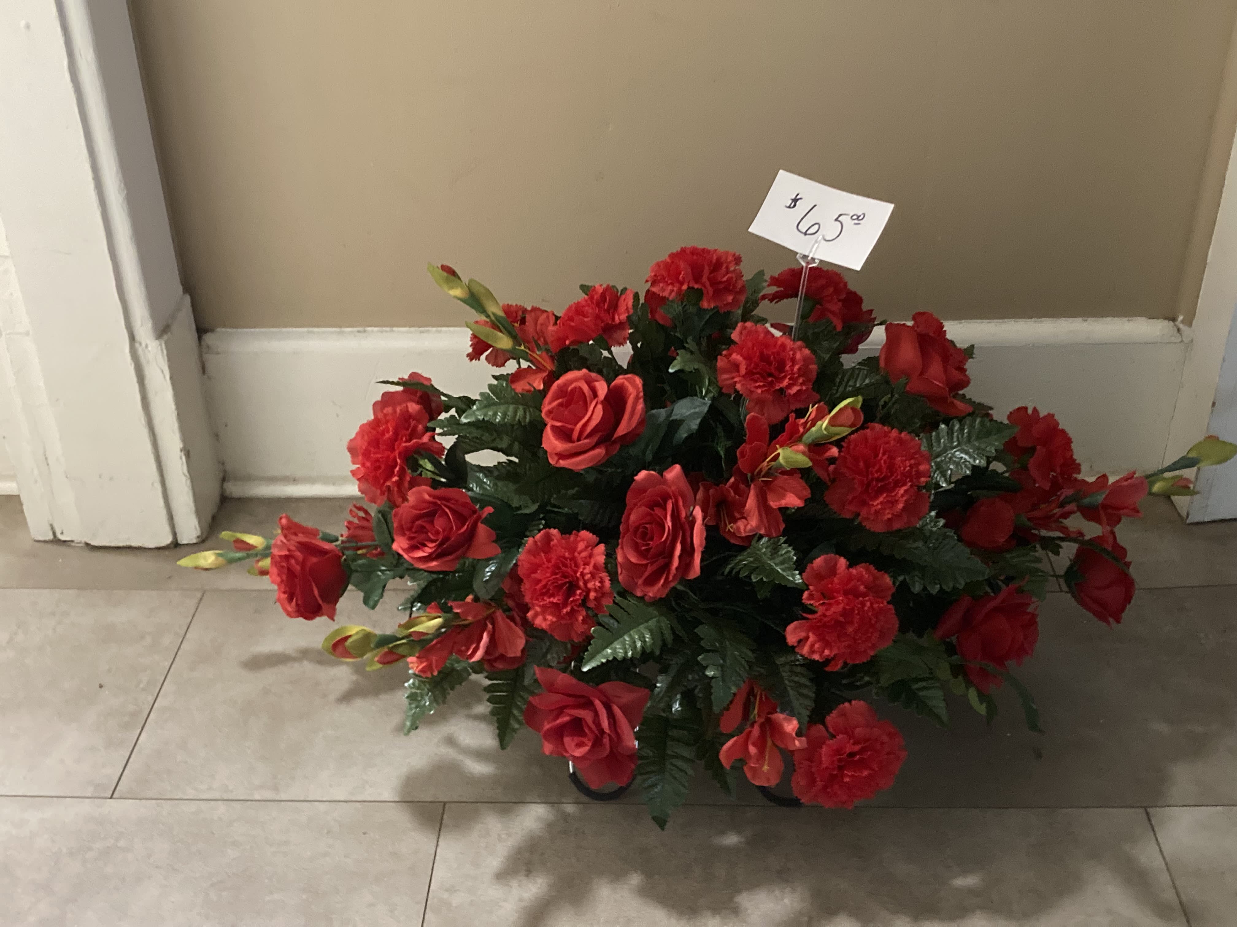 Red rose and carnation arrangement in a low container with a price tag