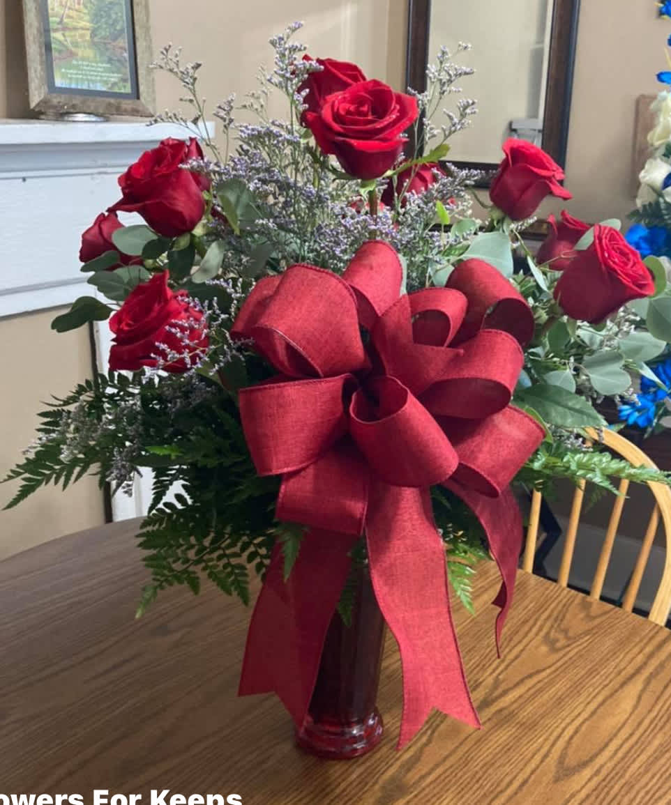 Red roses in a glass vase with a large red ribbon bow