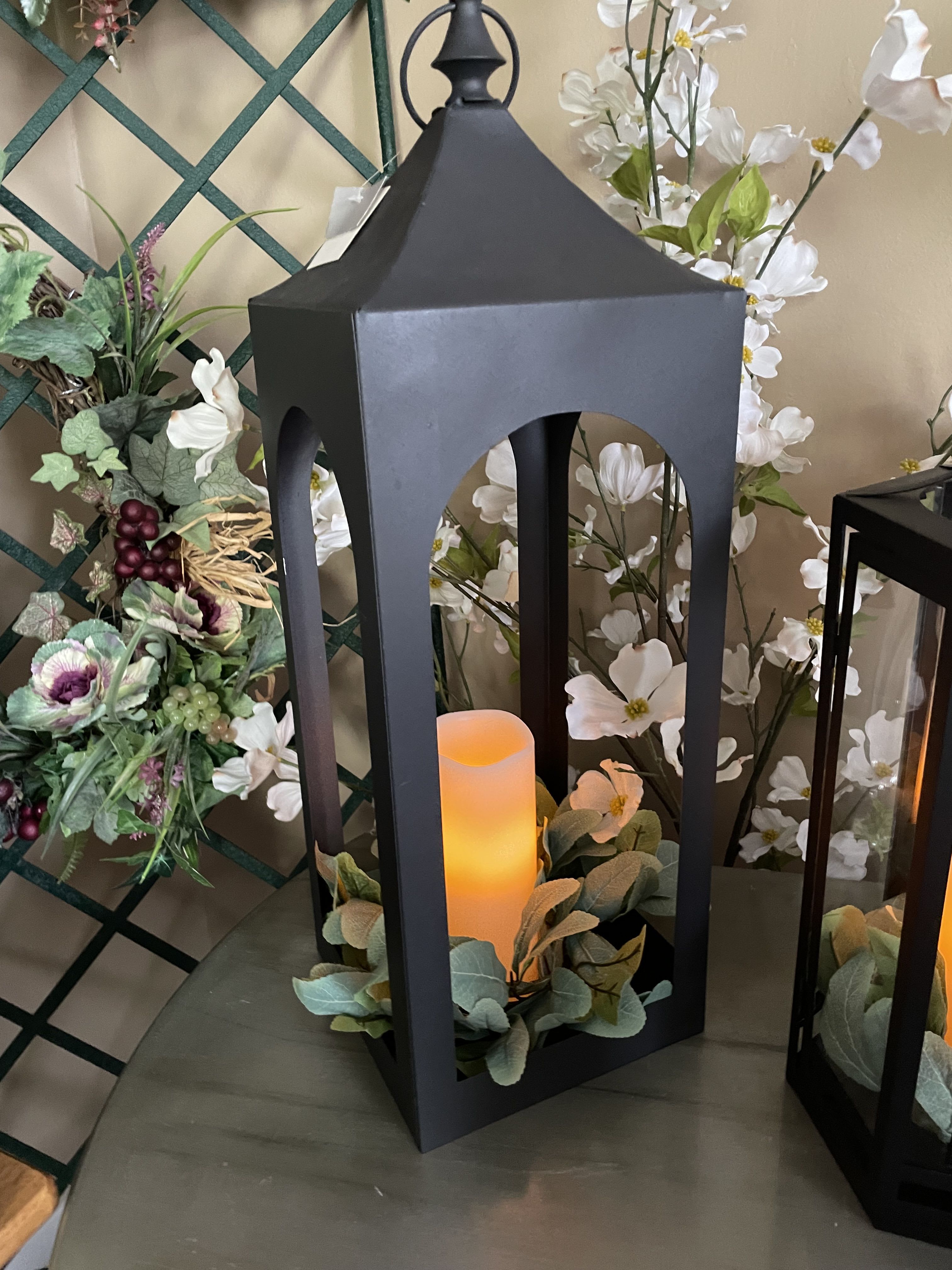 Black lantern with a glowing candle and white floral accents