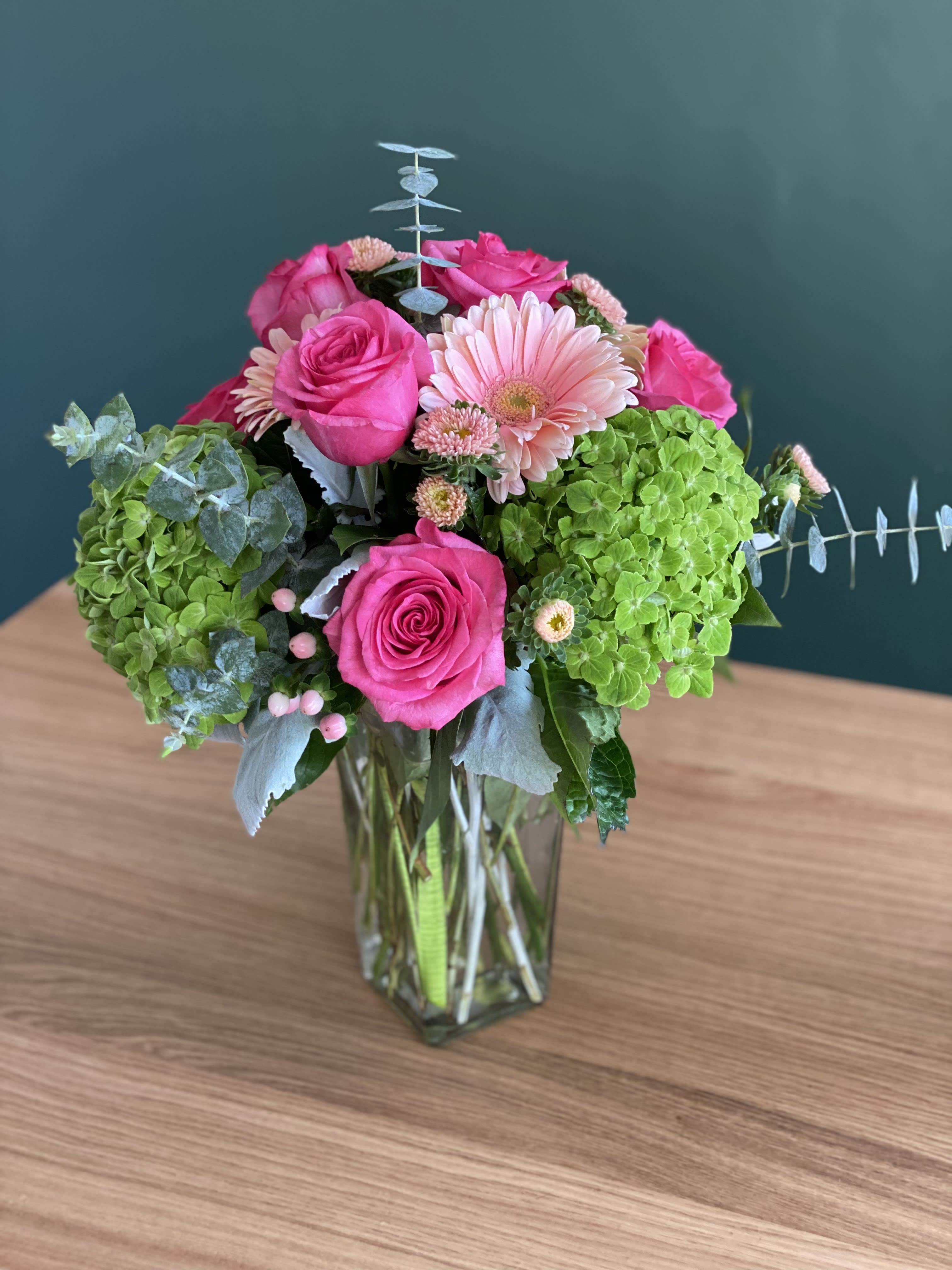 Pink roses and a pale gerbera daisy in a glass vase