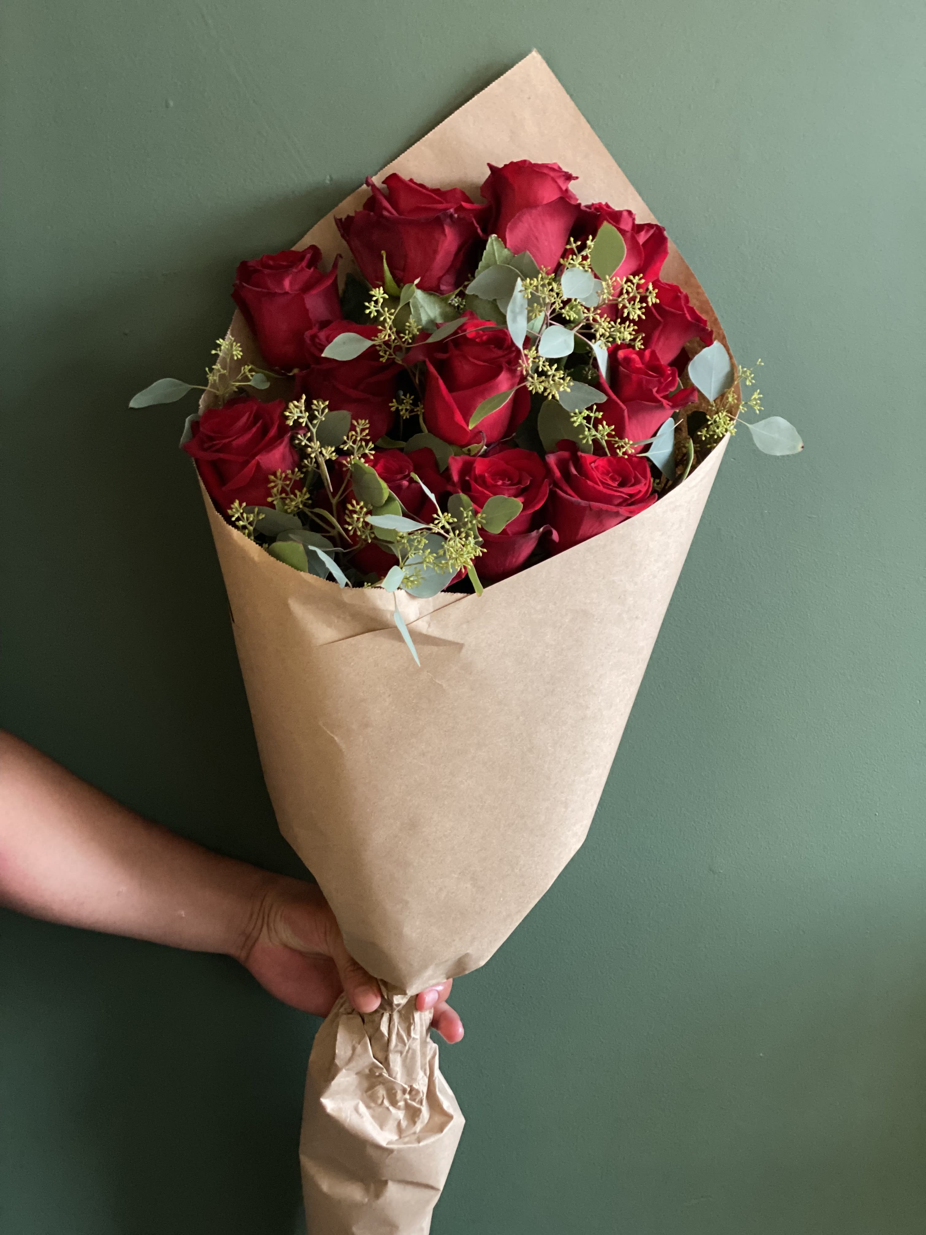 Hand-tied bouquet of red roses wrapped in brown paper