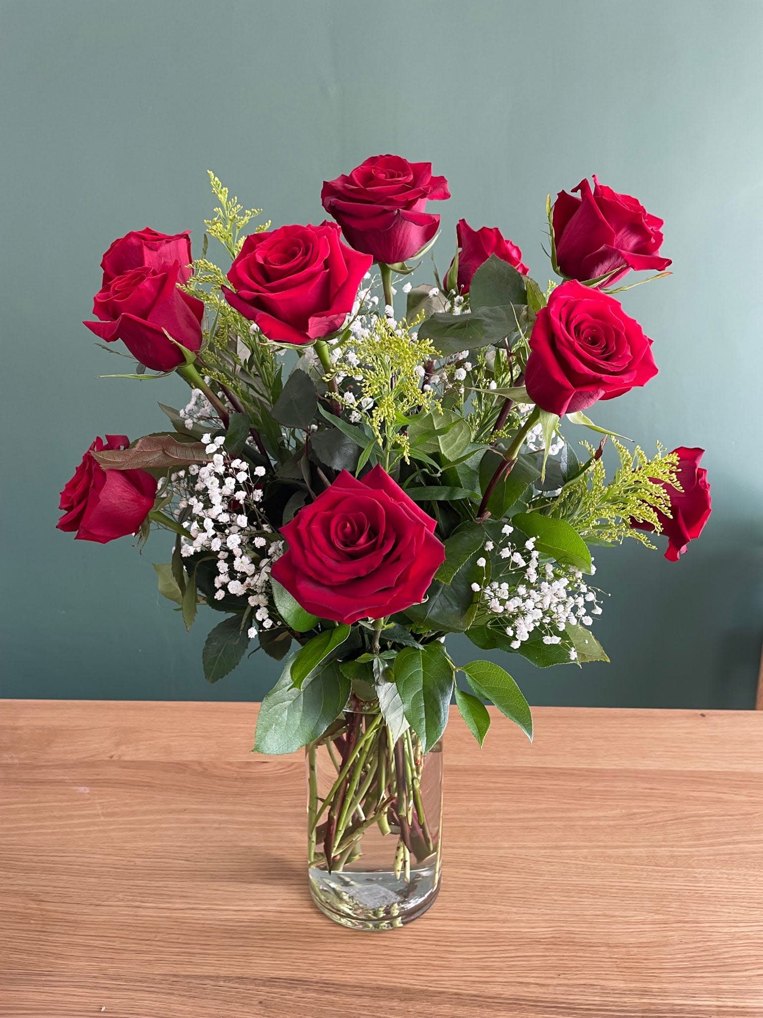 Red roses arranged in a clear glass vase with baby's breath