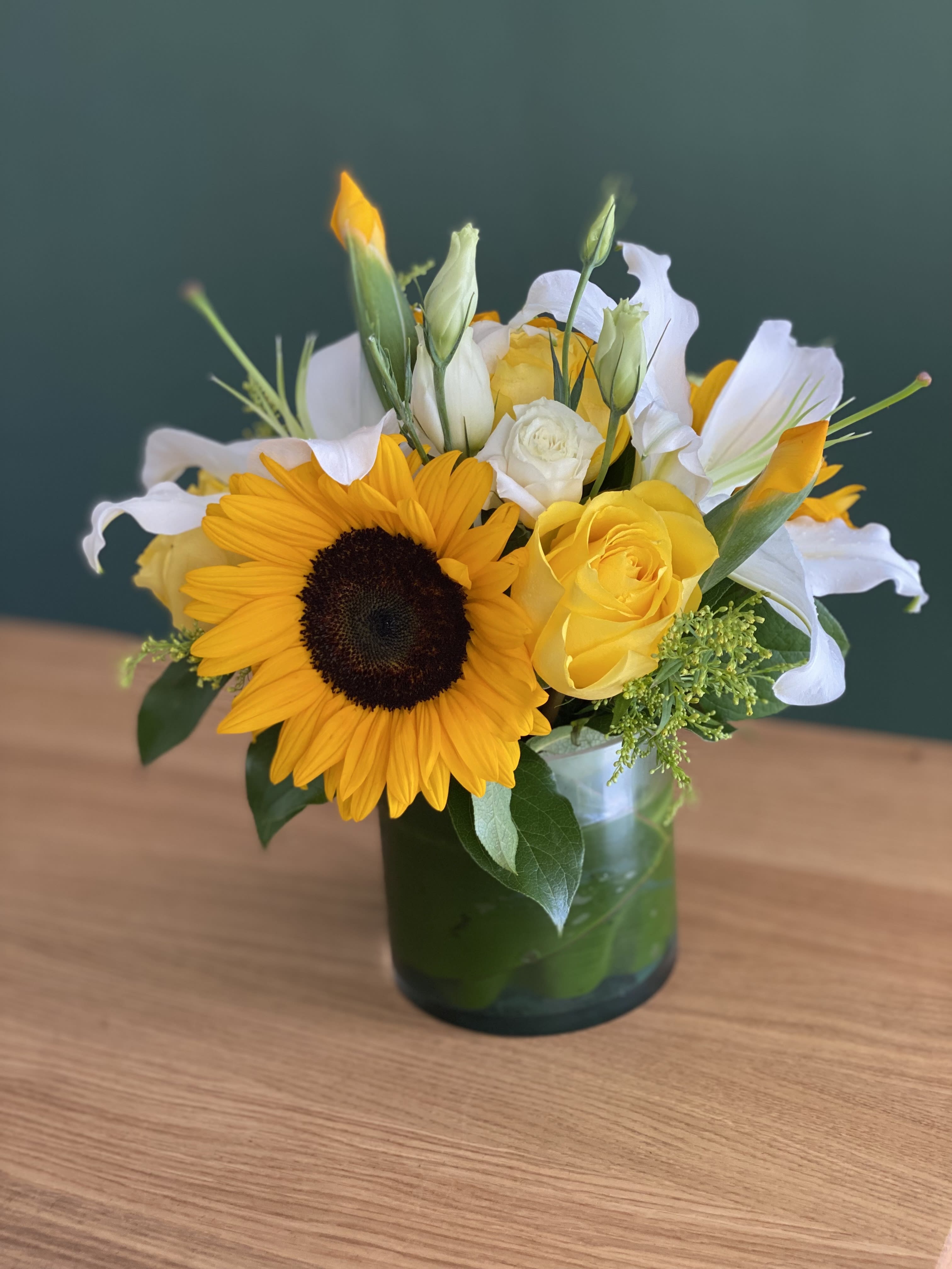 Sunflower and yellow rose bouquet in a glass vase