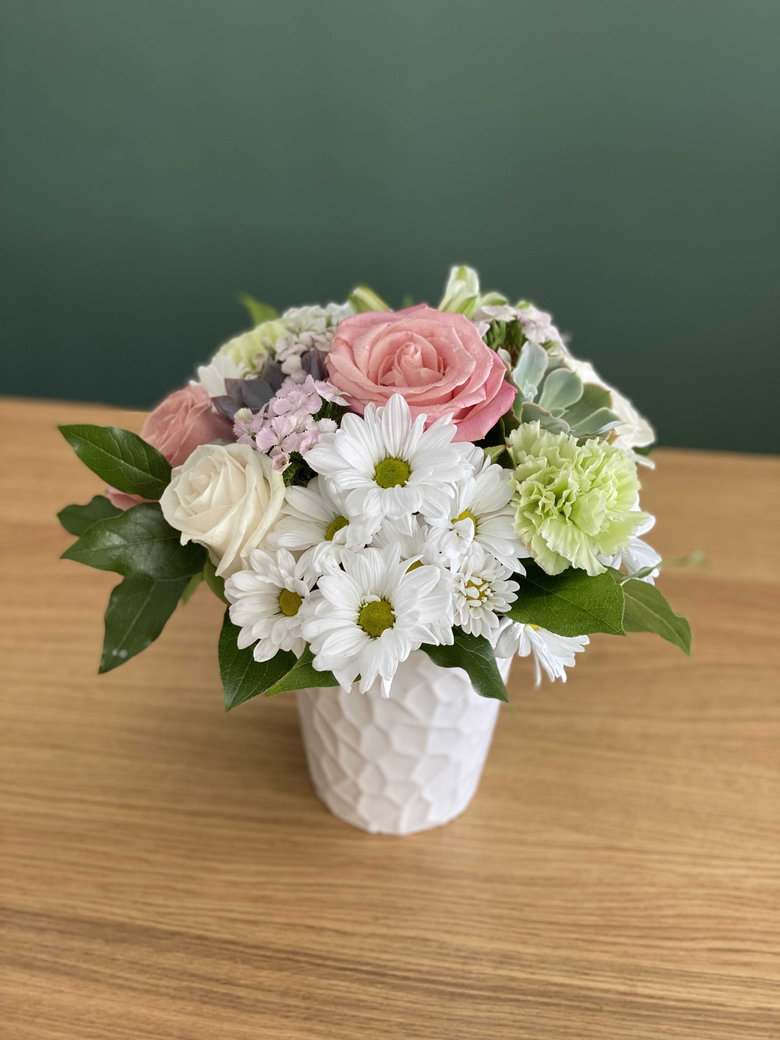 Pink and white flowers arranged in a white vase