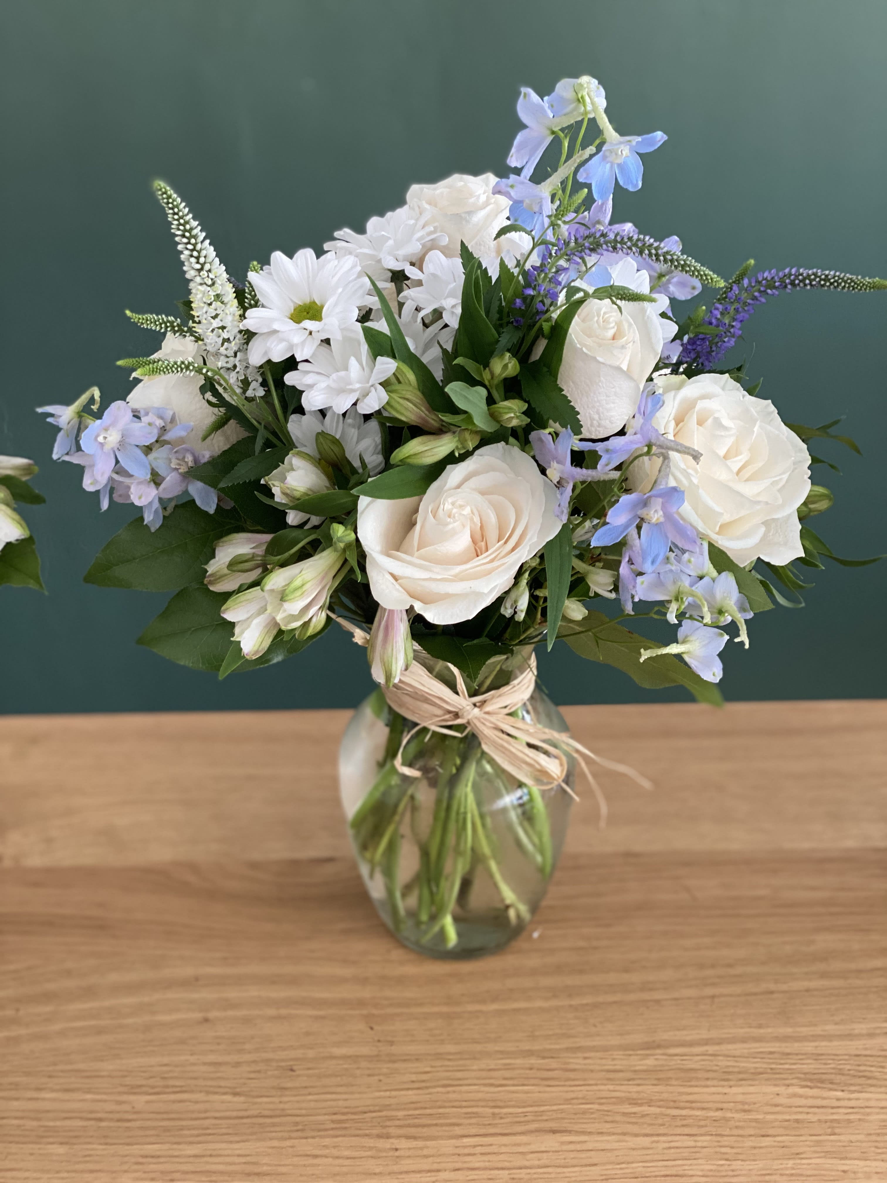 White roses and blue flowers arranged in a glass vase