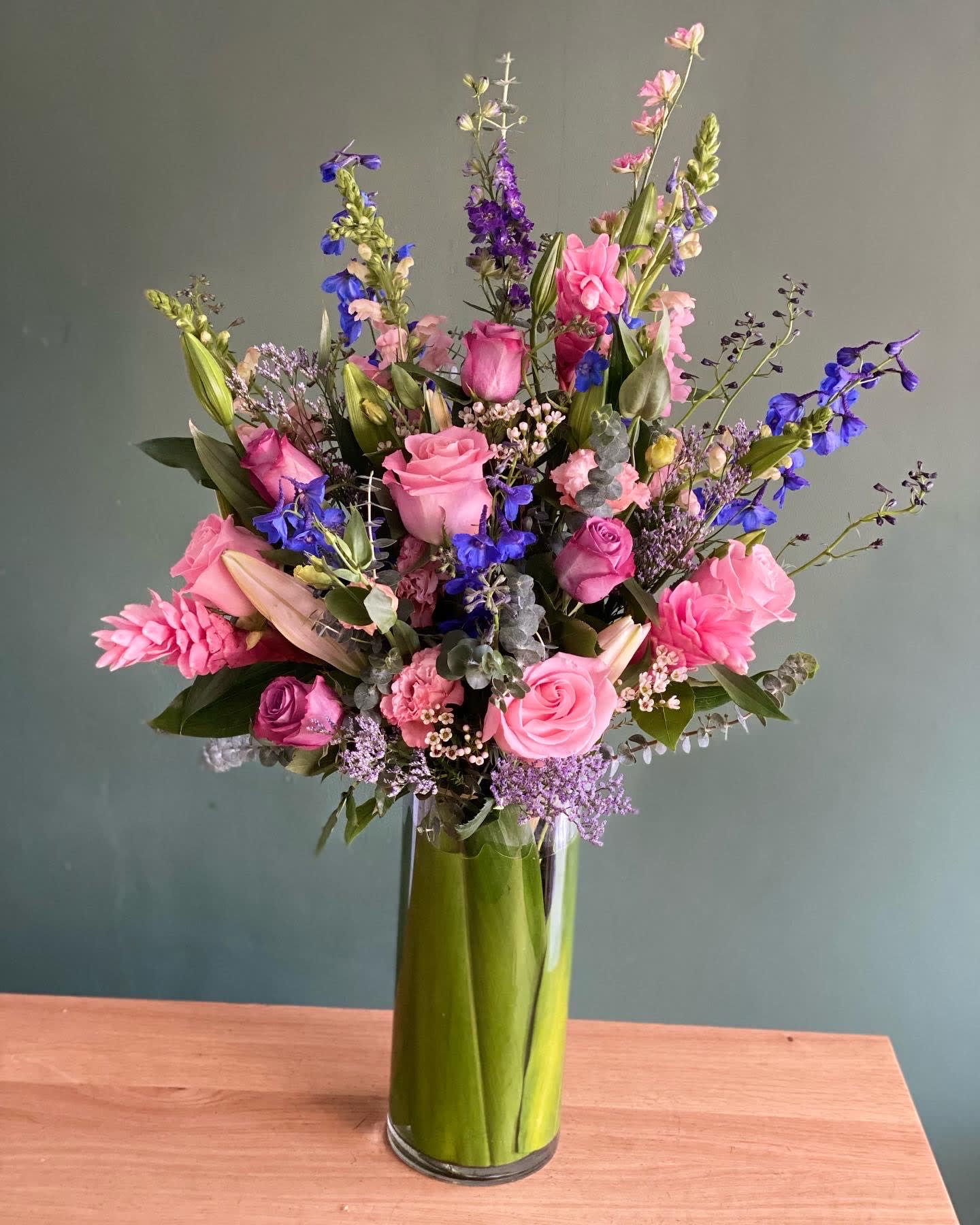Pink and purple mixed flower arrangement in a tall glass vase
