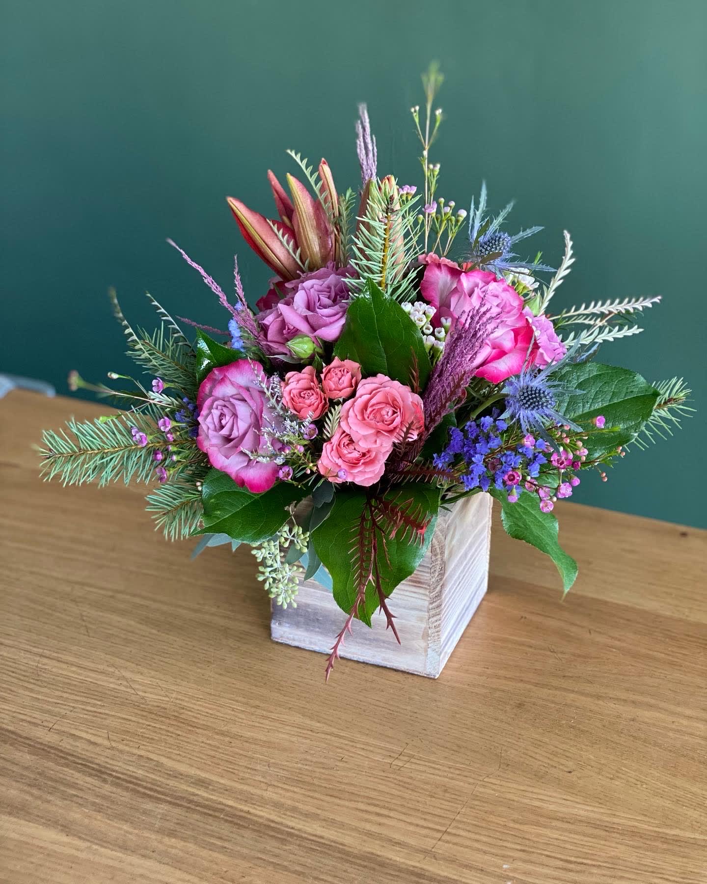 Pink and purple flower arrangement in a white wooden box