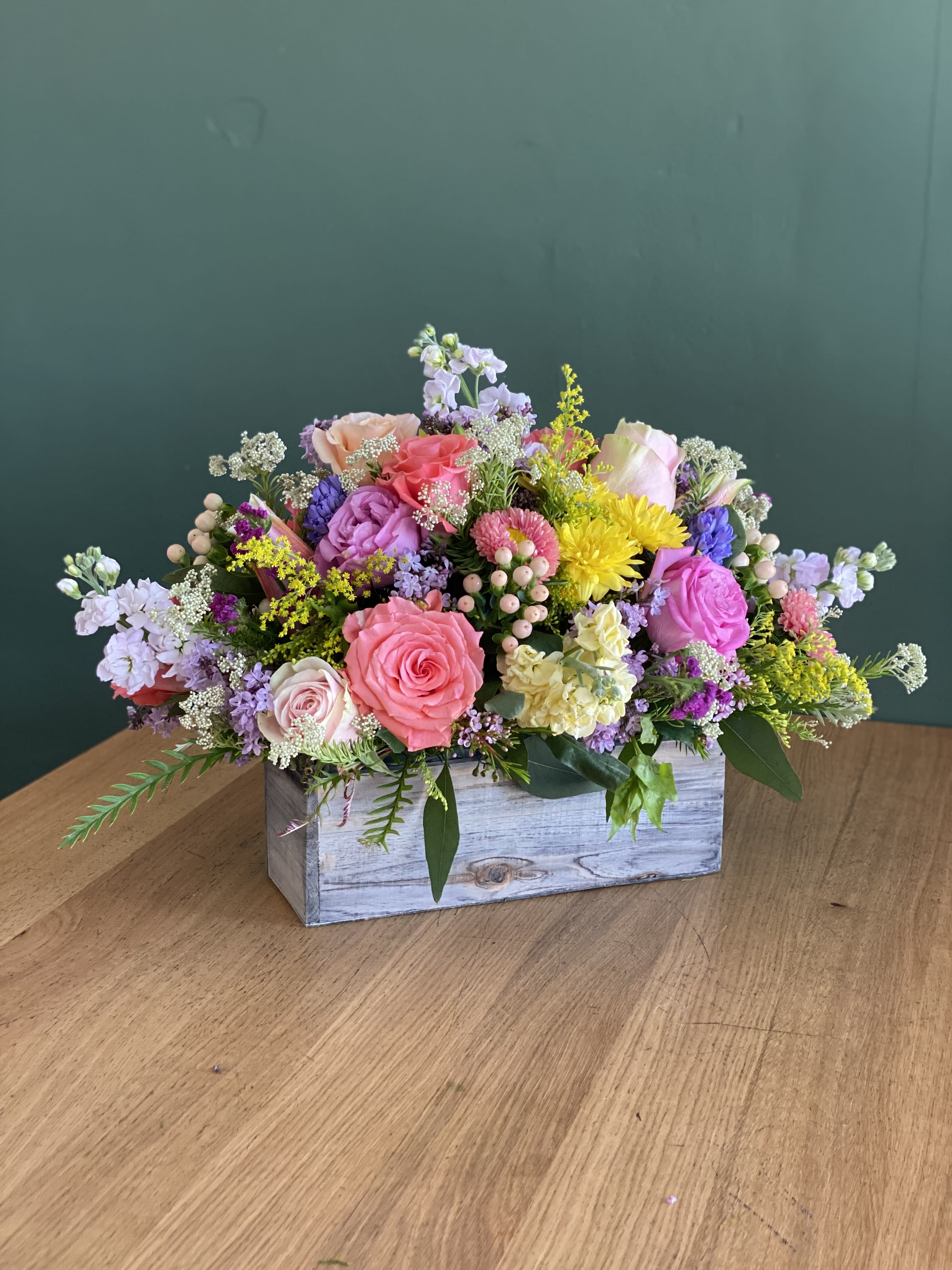 Mixed pink and purple flower arrangement in a wooden box