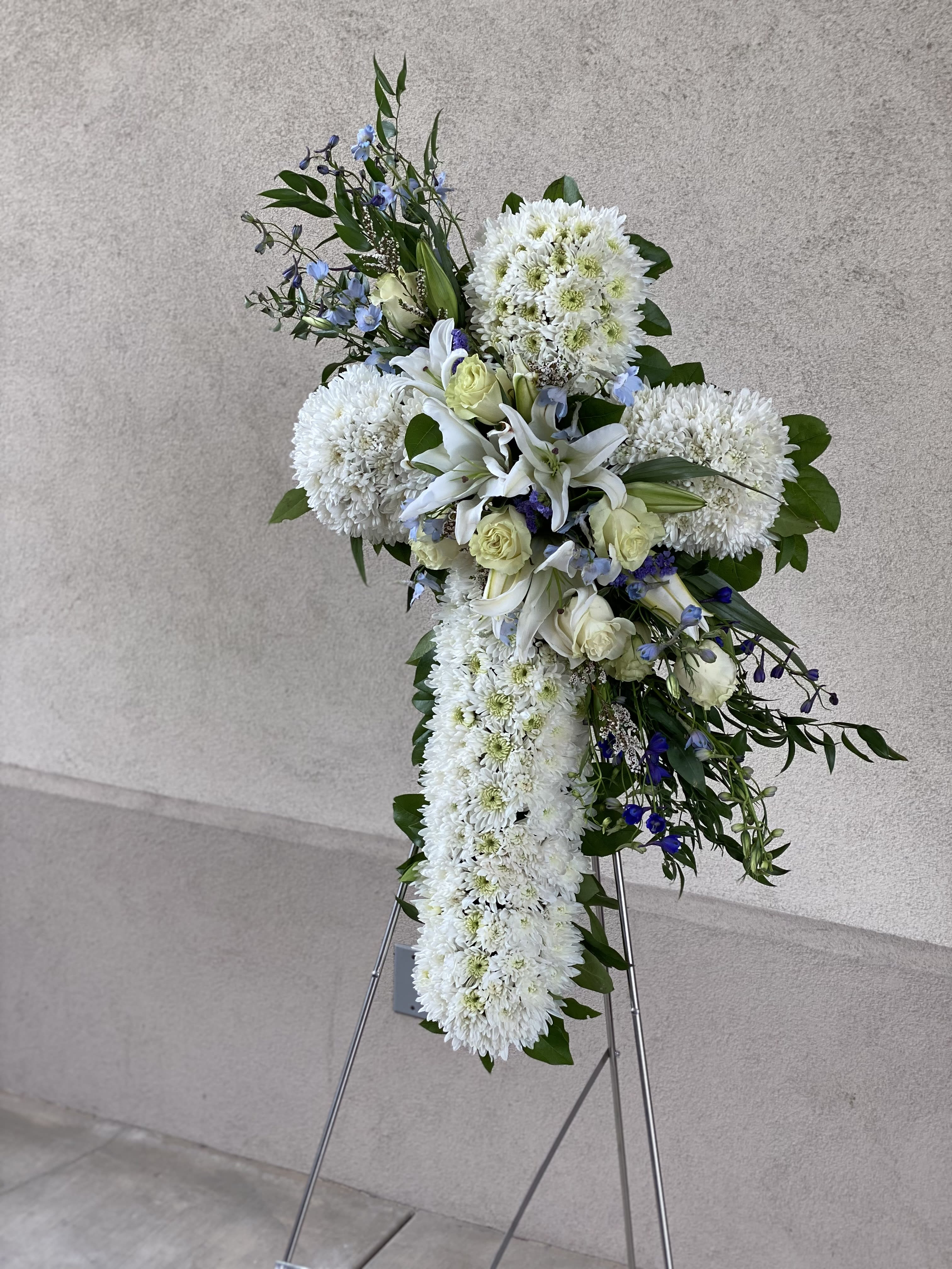 White floral standing spray with lilies, roses, and chrysanthemums on an easel