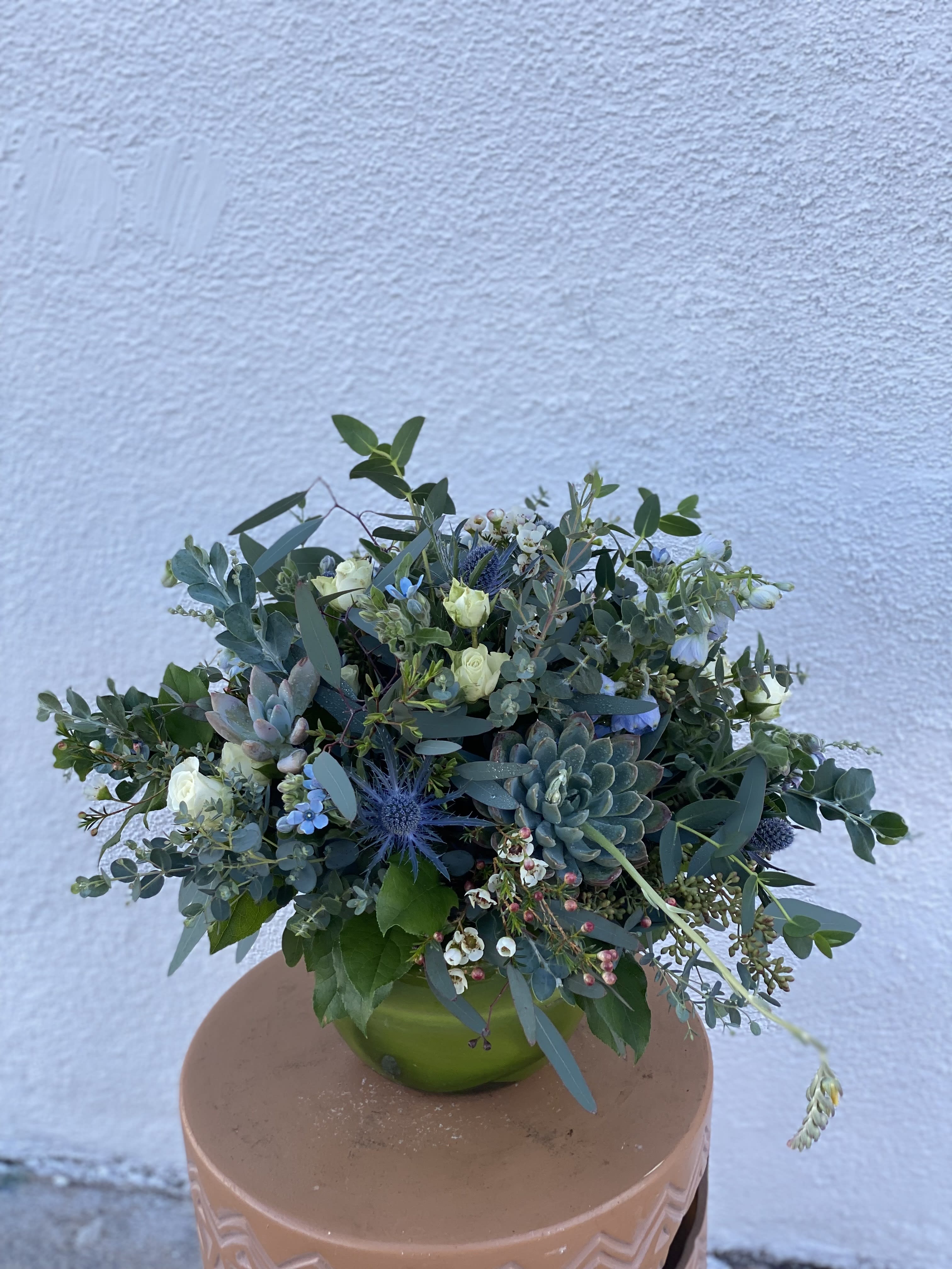 Mixed bouquet with succulents and small white flowers in a green vase