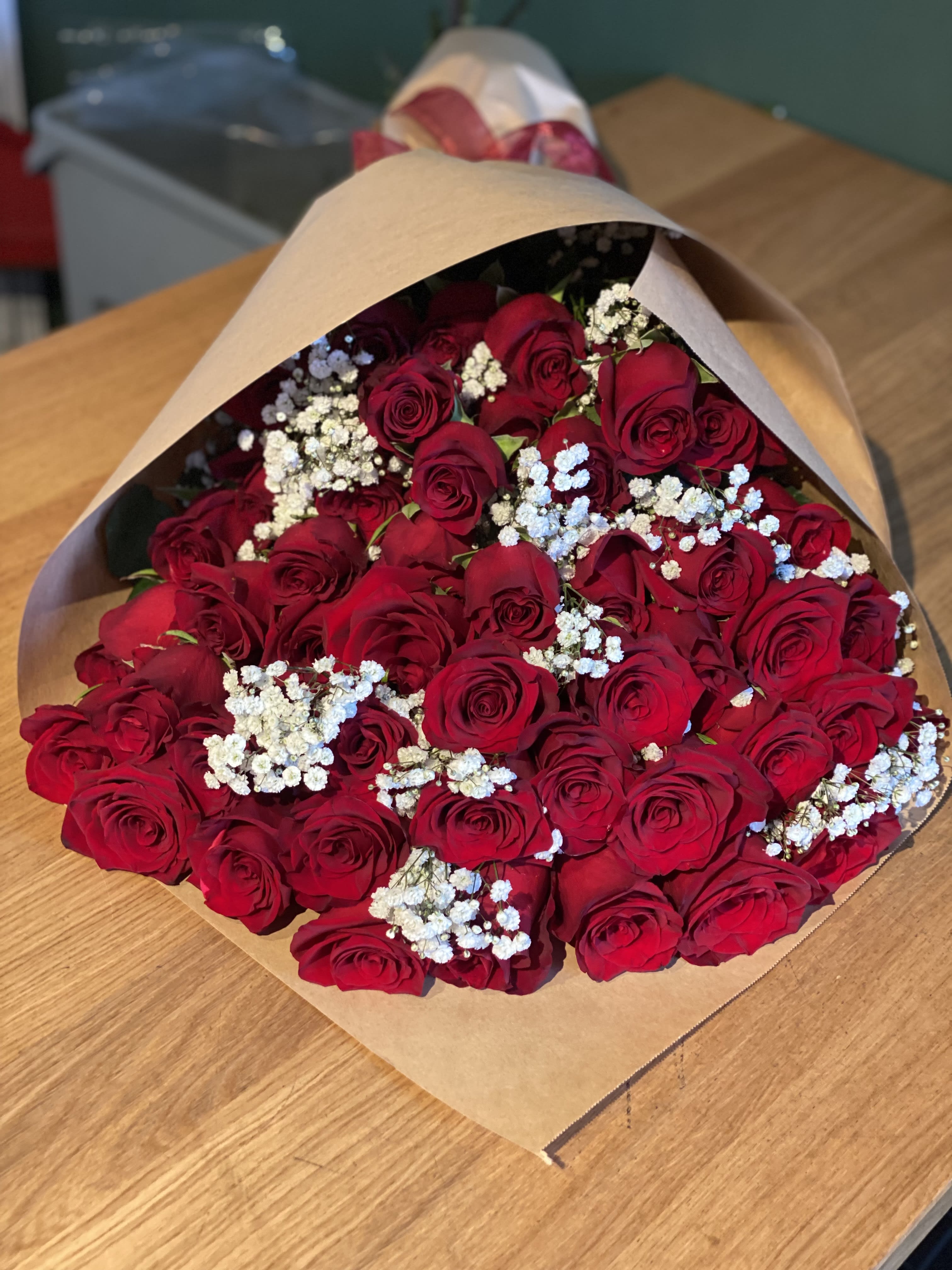 Bouquet of red roses with white baby's breath in brown paper