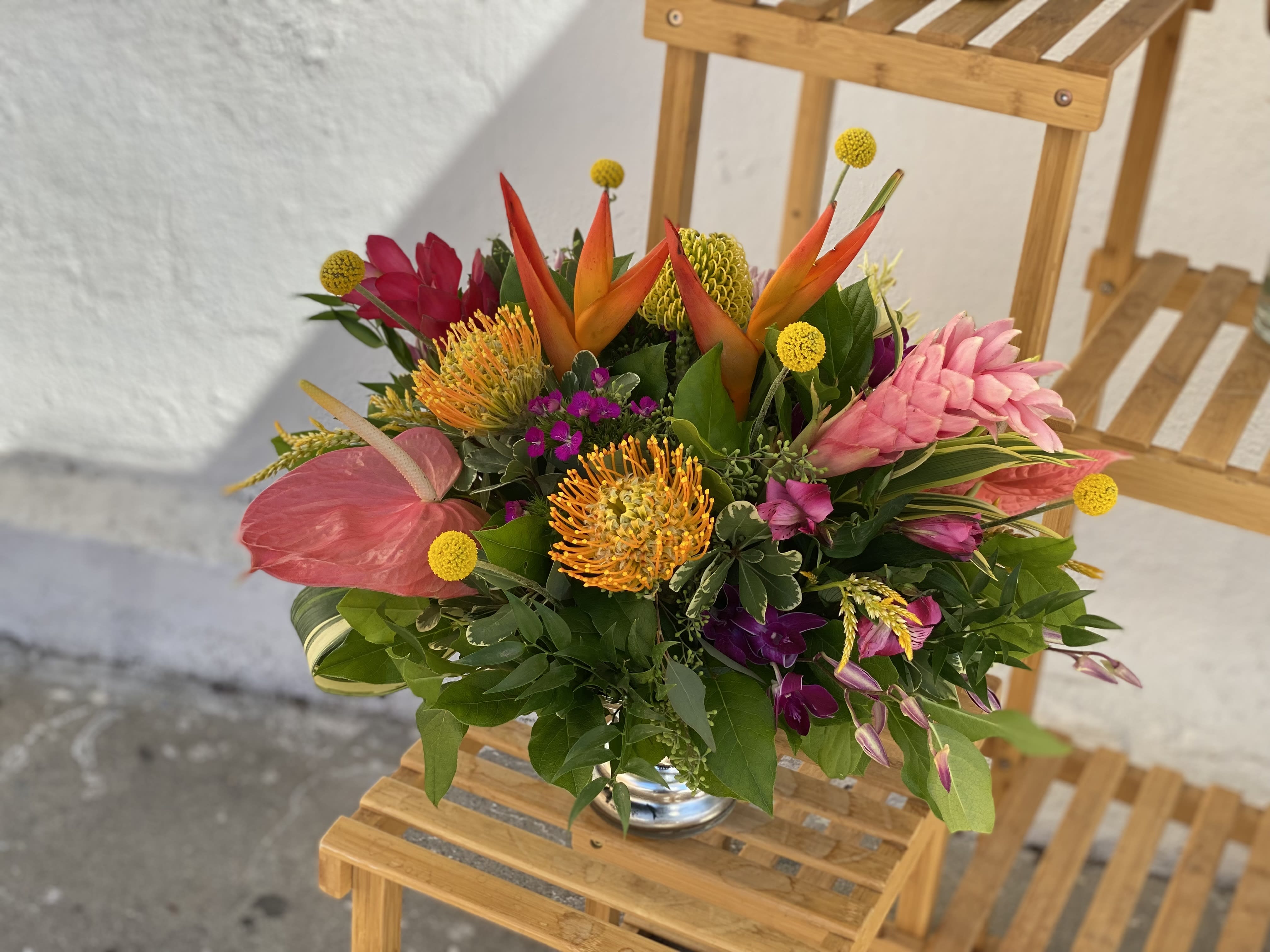 Tropical bouquet with pink, orange, and yellow flowers in a glass vase