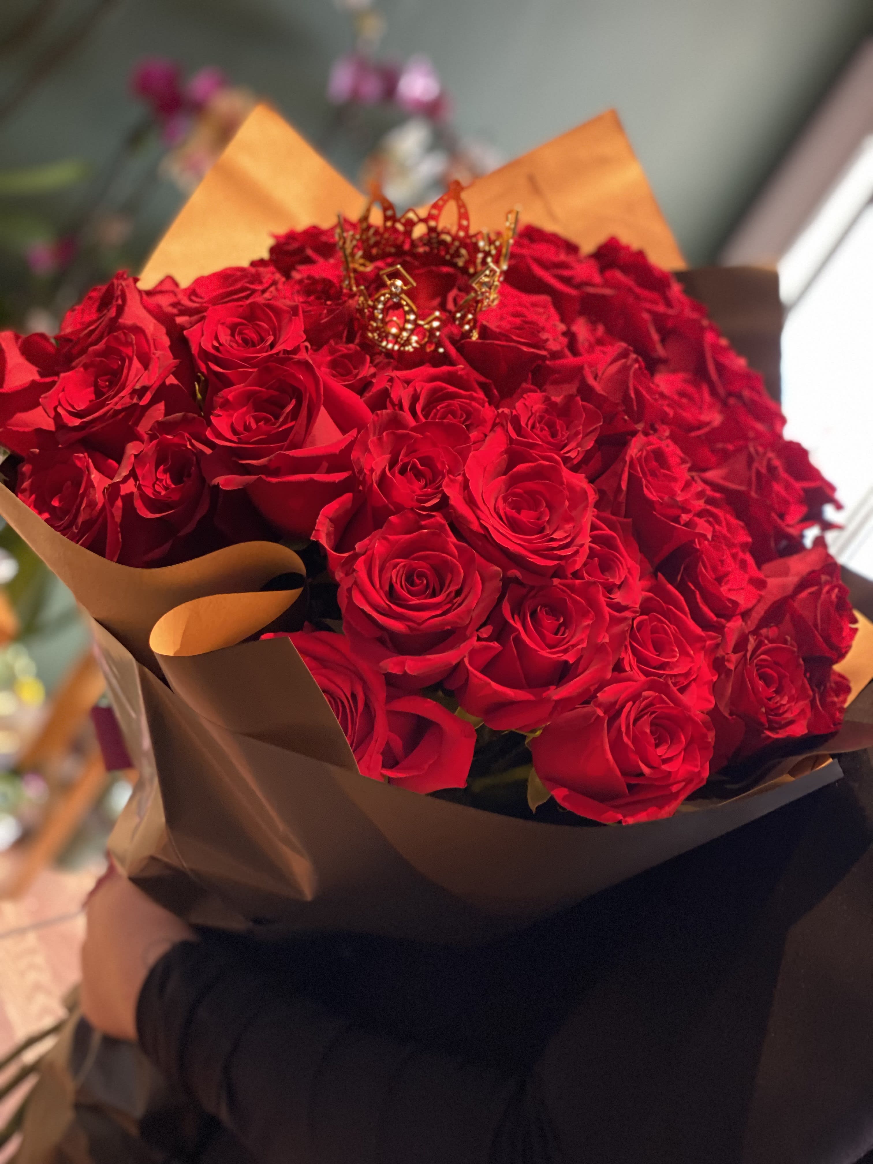 Bouquet of red roses wrapped in brown paper with a decorative crown